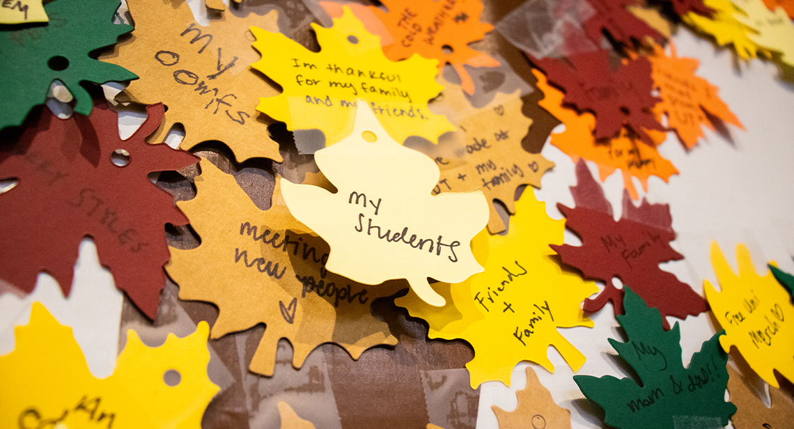 Paper leaves with thankful notes taped to the annual UHD Give Thanks Tree