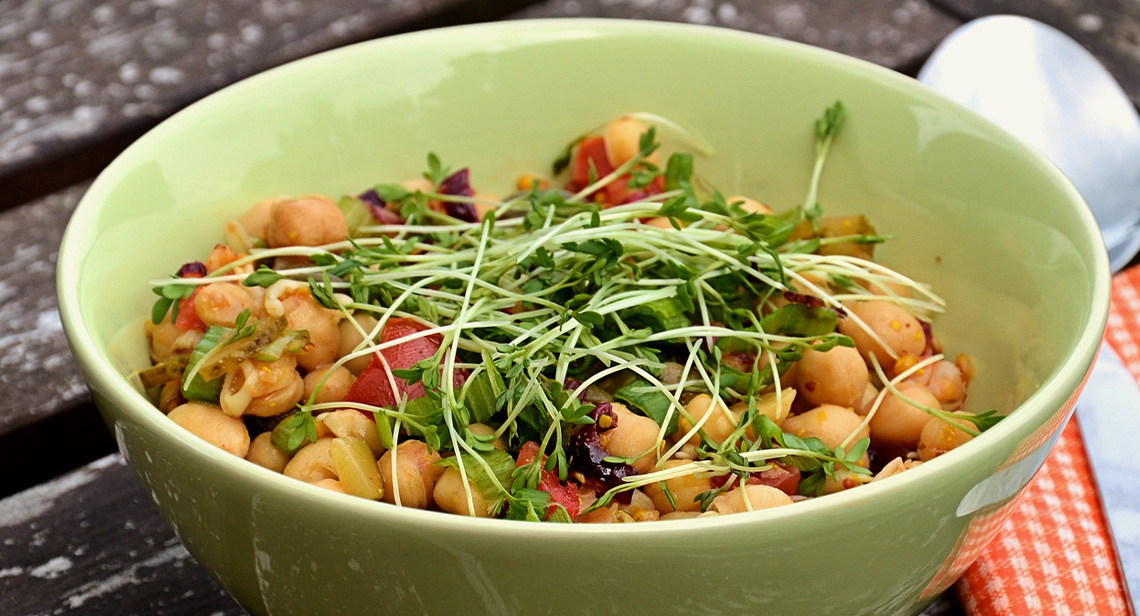 Close-up view of a bowl of chickpeas and other vegetables.