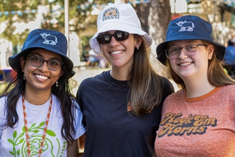 Three UT students pose together with UHD bucket hats at the fall 2023 Northside Bash