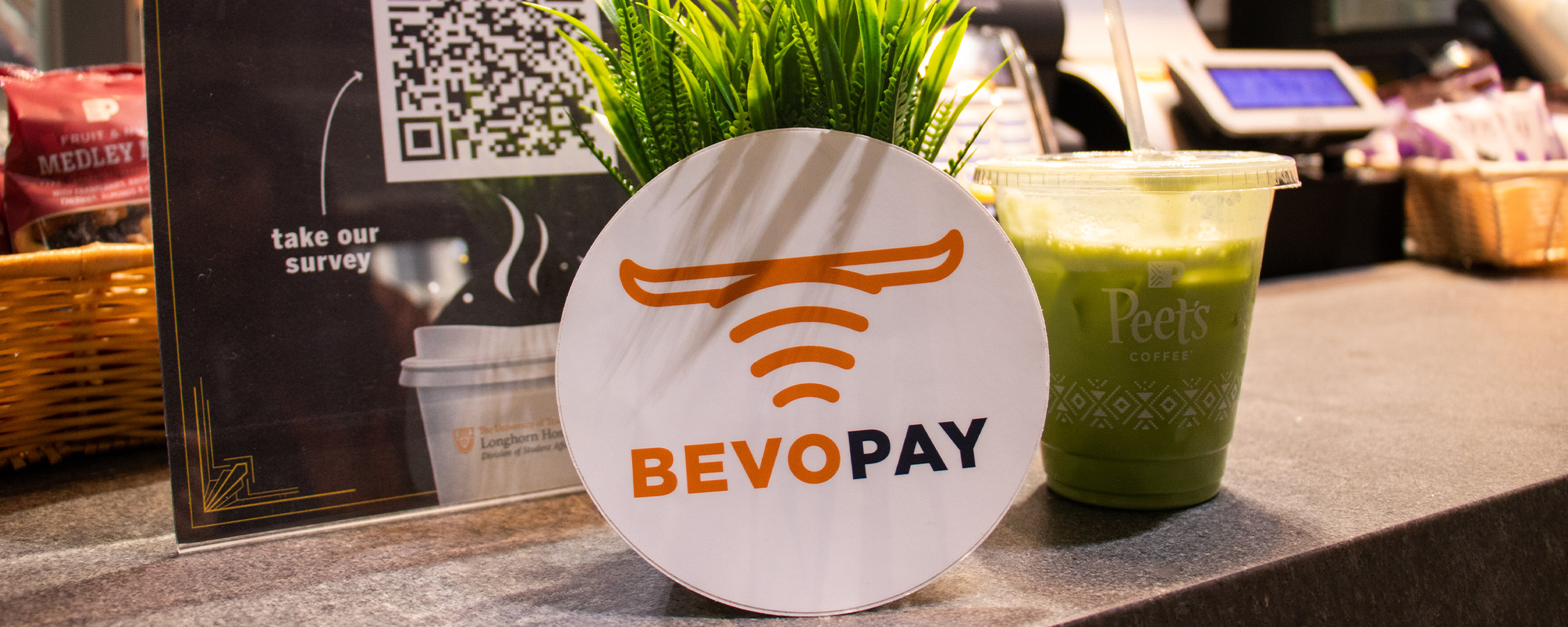 A Bevo Pay sticker and a Peet’s Coffee Iced Matcha Green Tea Latte displayed promotionally on the ordering counter at Littlefield Patio Cafe. 