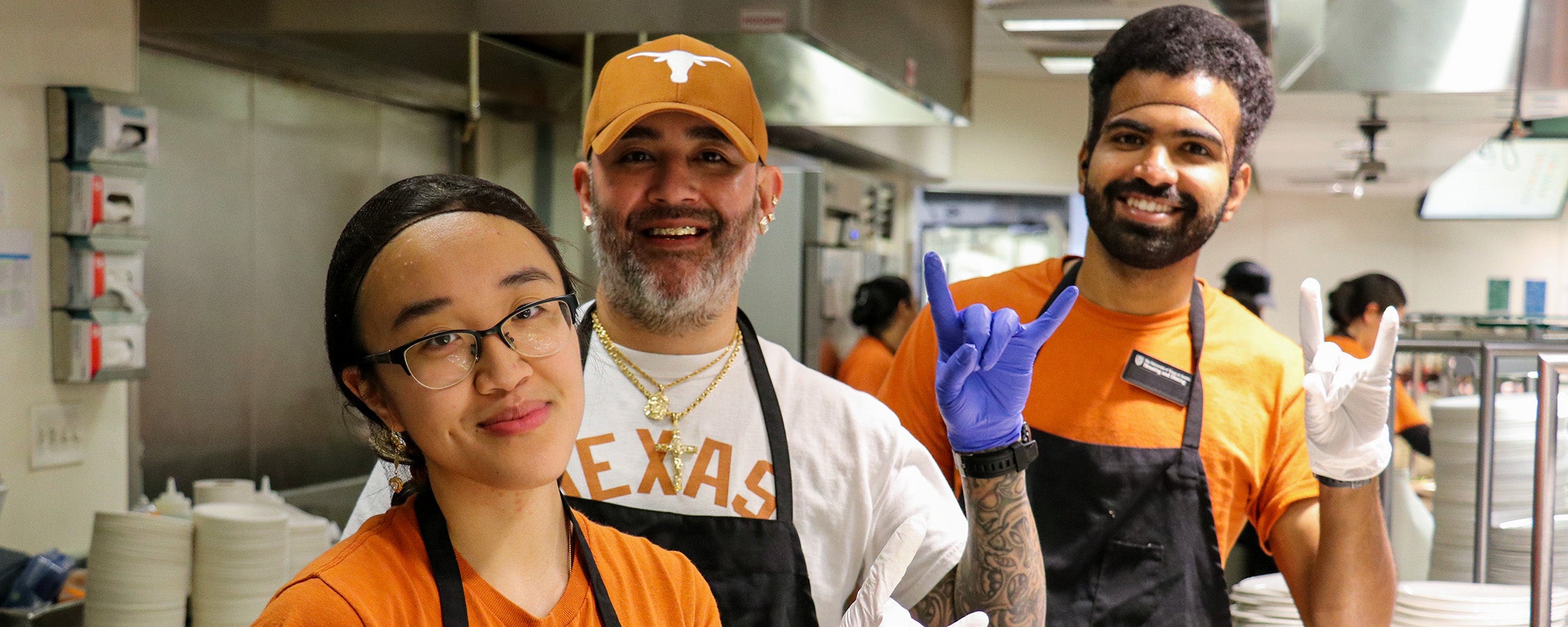 Three UHD staff members smiling in the Kins Dining kitchen