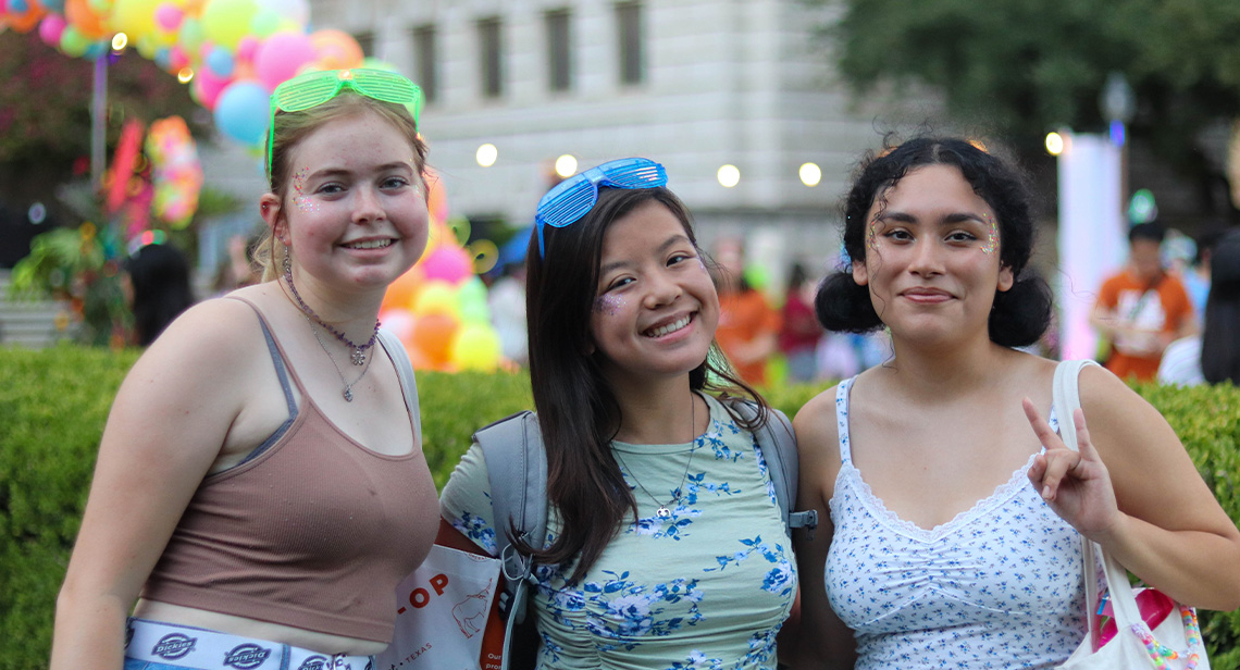 Three UT students pose together at Longhorn Welcomes Neon Circus event