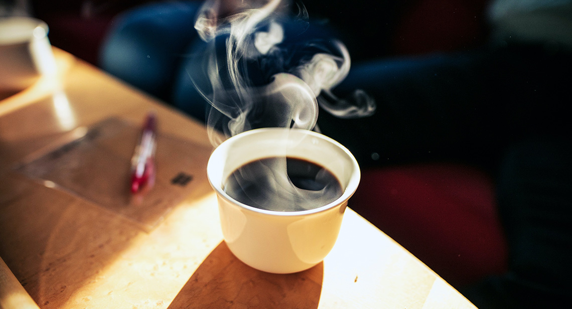 A steaming cup of coffee on a table.