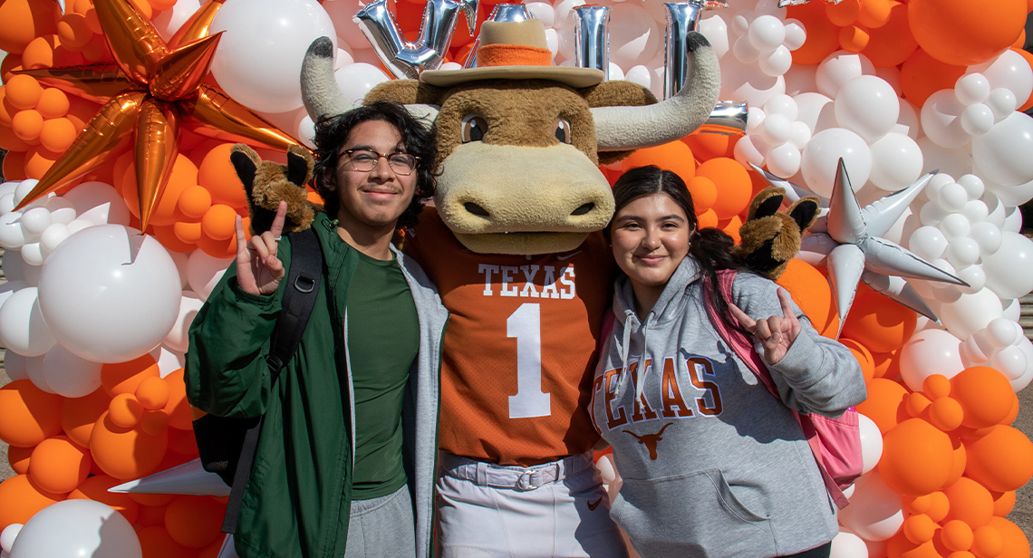 Two UT students pose with the HookEm mascot.