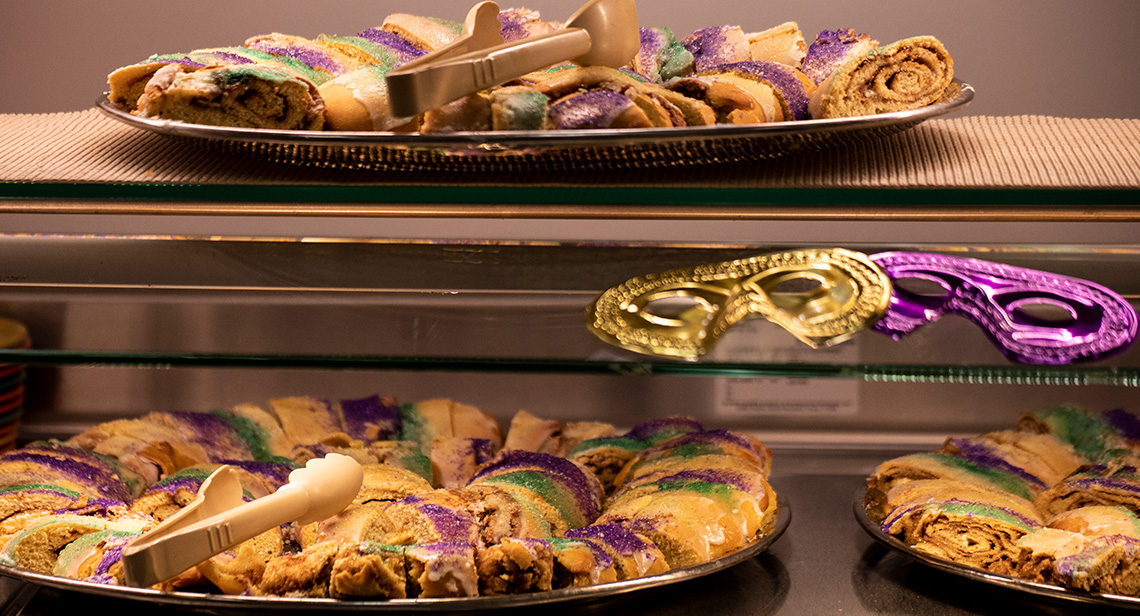 Trays of king cake and decorative masks on display