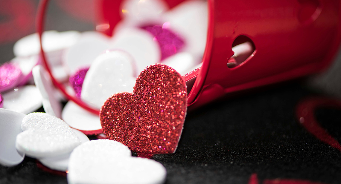 Glittery hearts cascade out of a decorative bucket. 