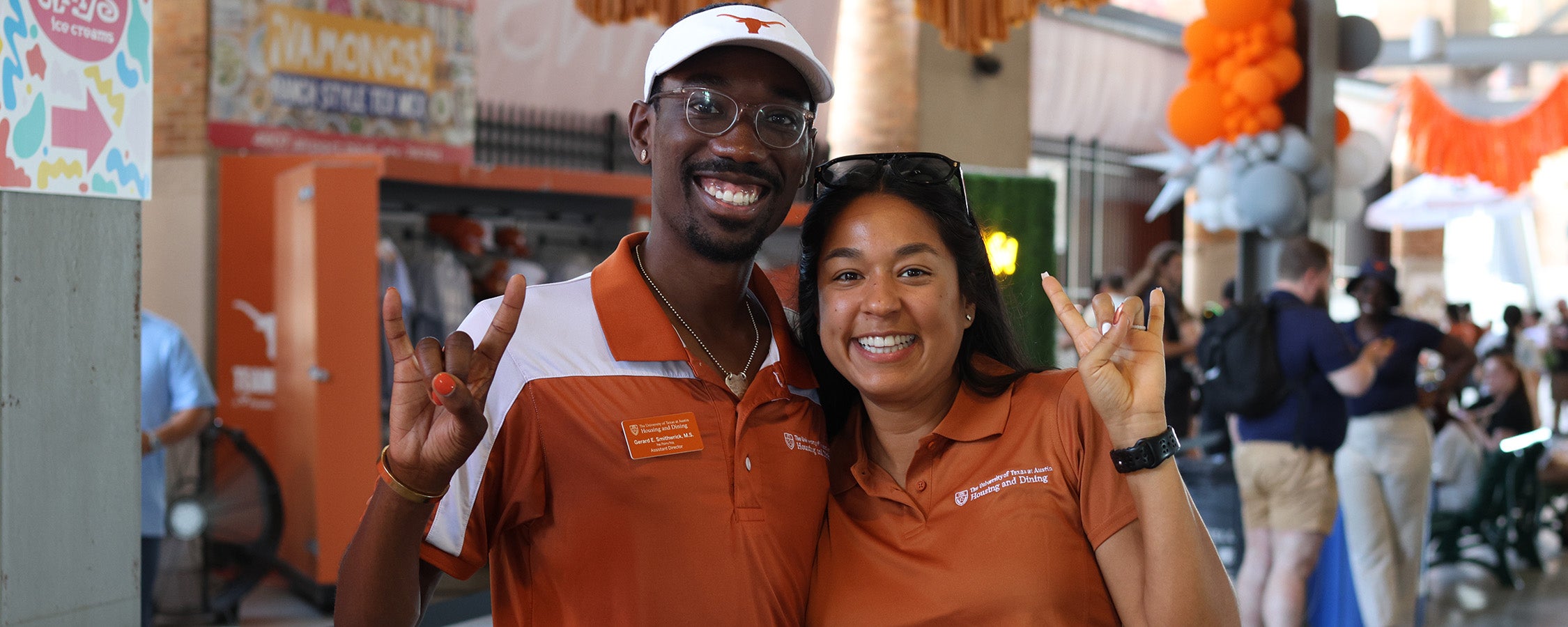 Two UHD employees with Hook'em horns gestures