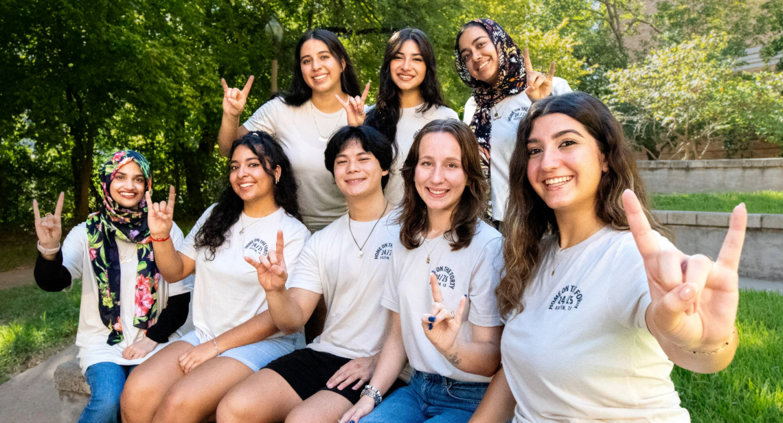 Eight UT students pose together in Home on the Forty shirts outside of San Jacinto Hall.