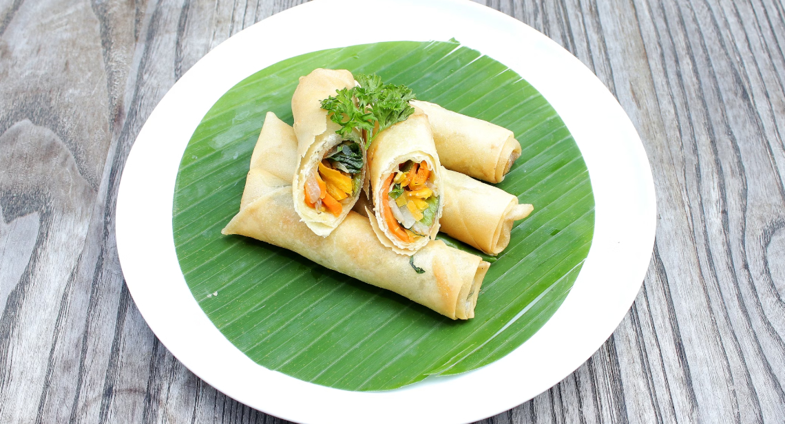  A plate of spring rolls served on a banana leaf.