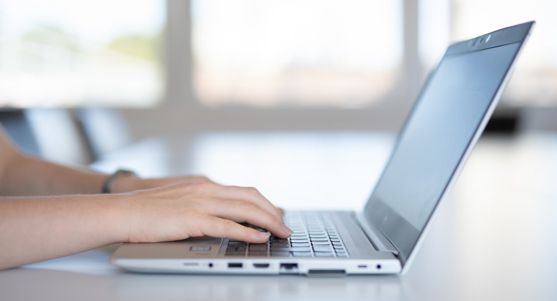 Hands typing on a laptop keyboard.