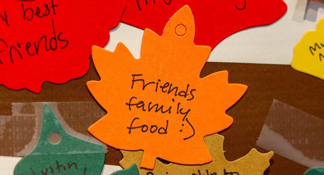 A leaf on the “Give Thanks Tree” that reads, “Friends, family, food”.