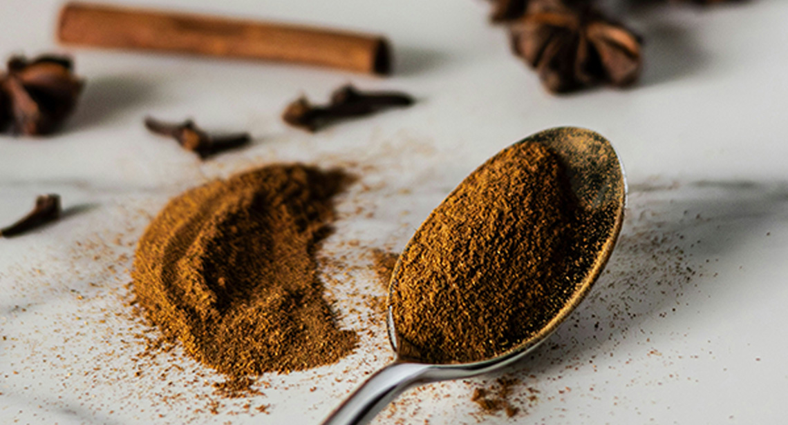 A spoon next to various spices on a table. 