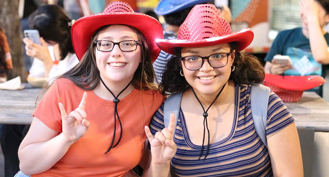 Two UT students pose together wearing cowboy hats. 