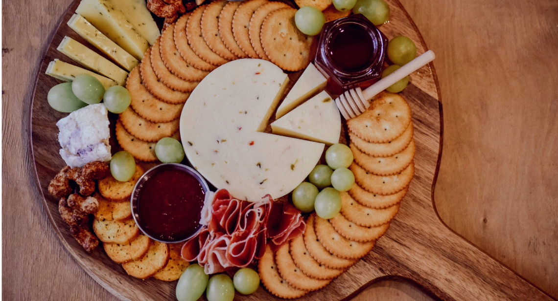 Charcuterie board with an assortment of crackers, cheese, meats and spreads