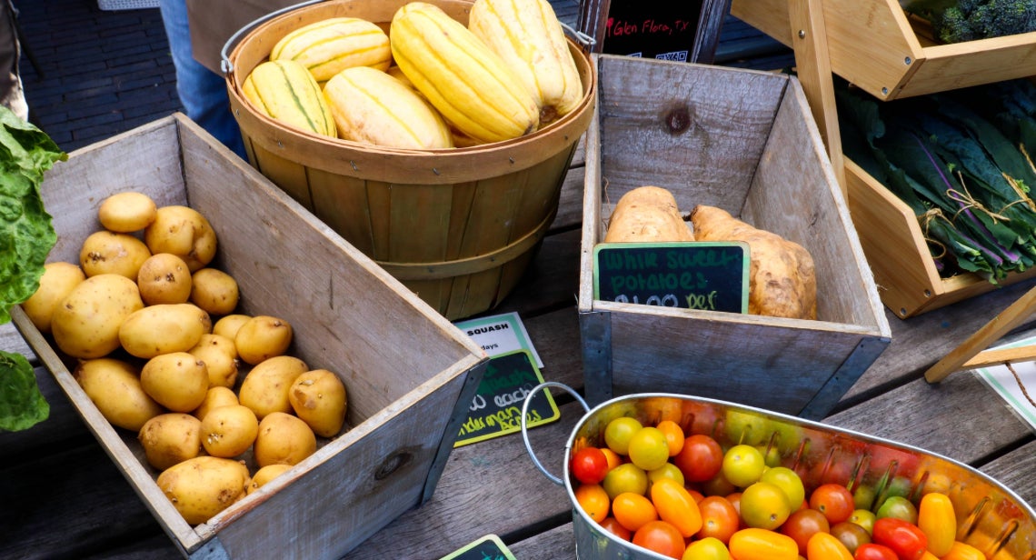 An assortment of produce including potatoes, squash and tomatoes in buckets at UT Farm Stand on Jester Corner