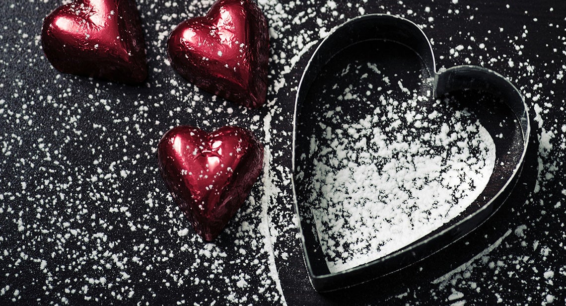 A heart-shaped cookie cutter and chocolates dusted with powdered sugar.