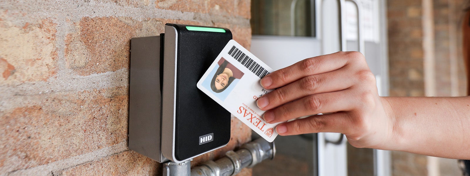 A person tapping their UT ID card on a door card reader.