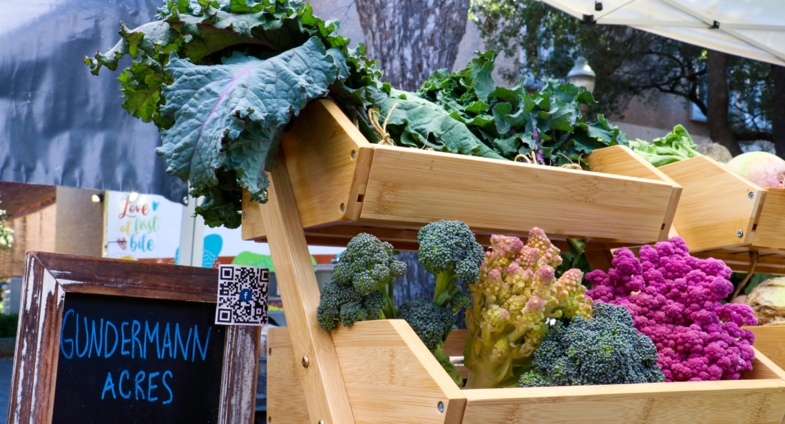 Colorful veggies like kale and cauliflower in wooden crates from Gundermann Acres at the UT Farm Stand Market