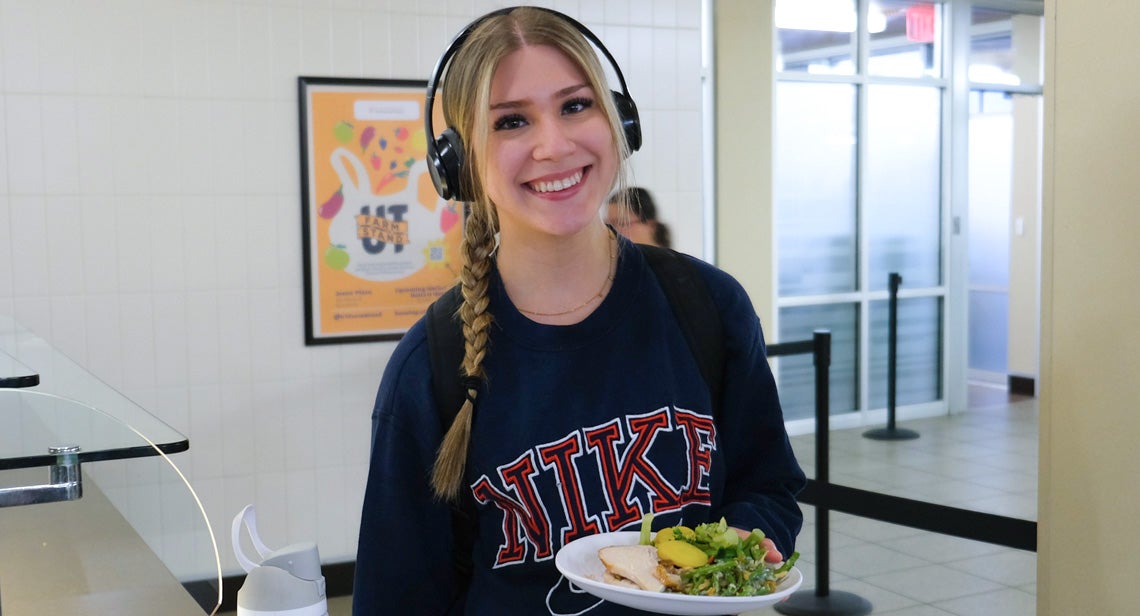 A UT student posing with a plate of food inside a dining hall