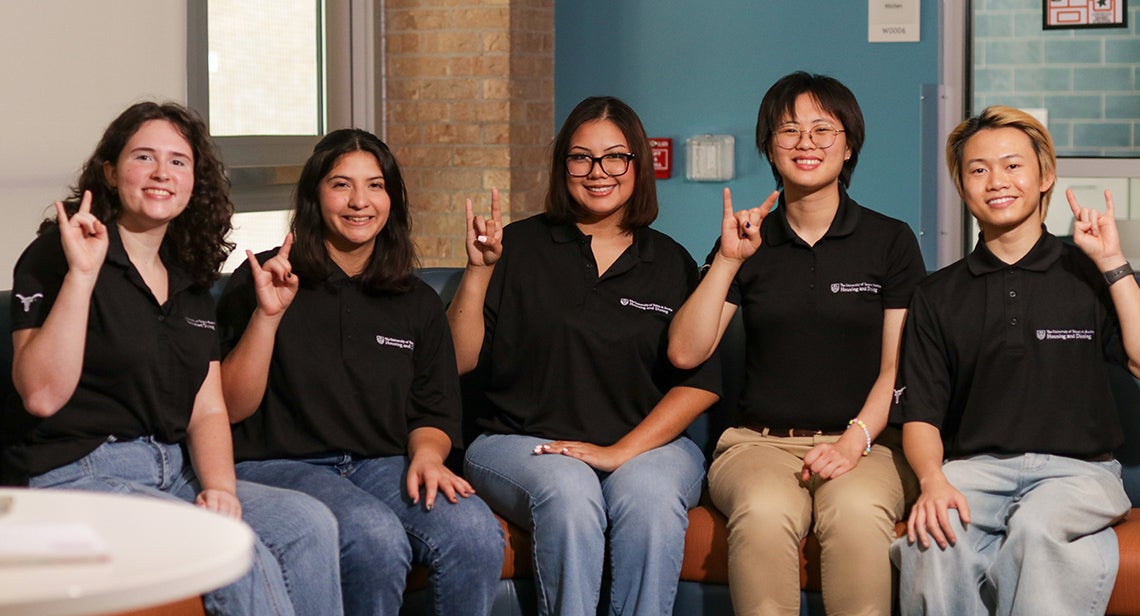 Five UT Resident Assistants pose together while making the Hook ‘em hand sign