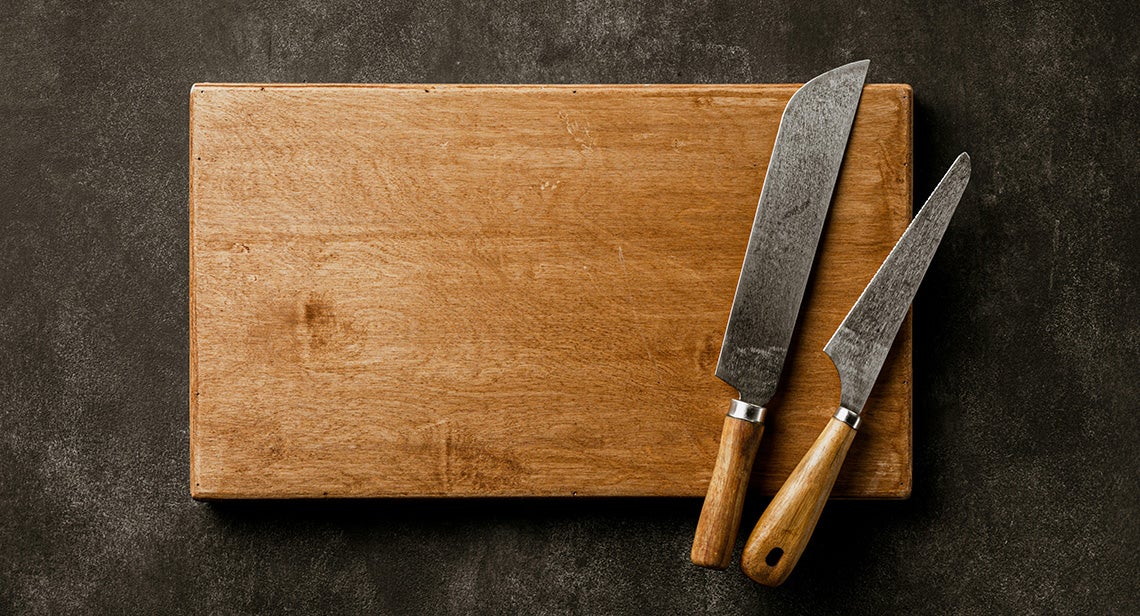 Two knives on top of a wooden cutting board