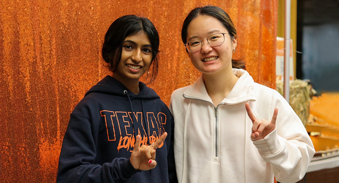 Two UT students make the Hook ‘Em hand sign at the Friendsgiving event.