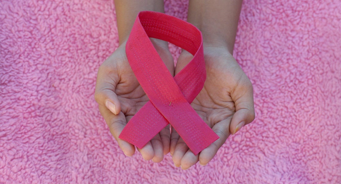 Hands hold a pink breast cancer awareness ribbon