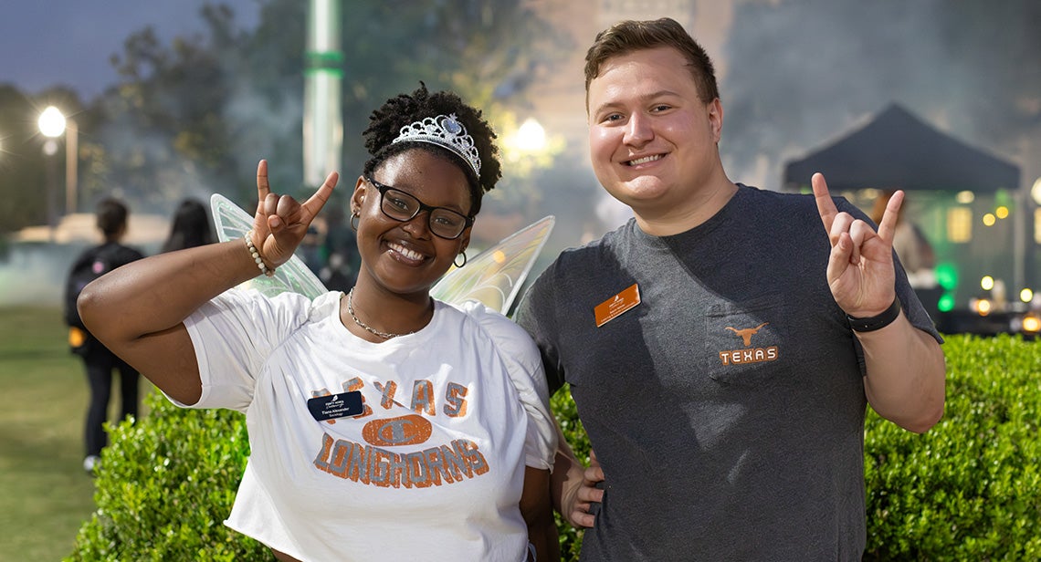 Two people hold up hook ‘em hand signs.