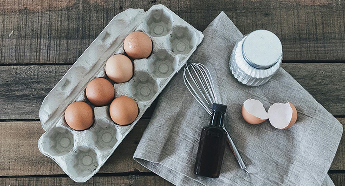 A half-filled egg carton beside a towel with baking supplies on top.