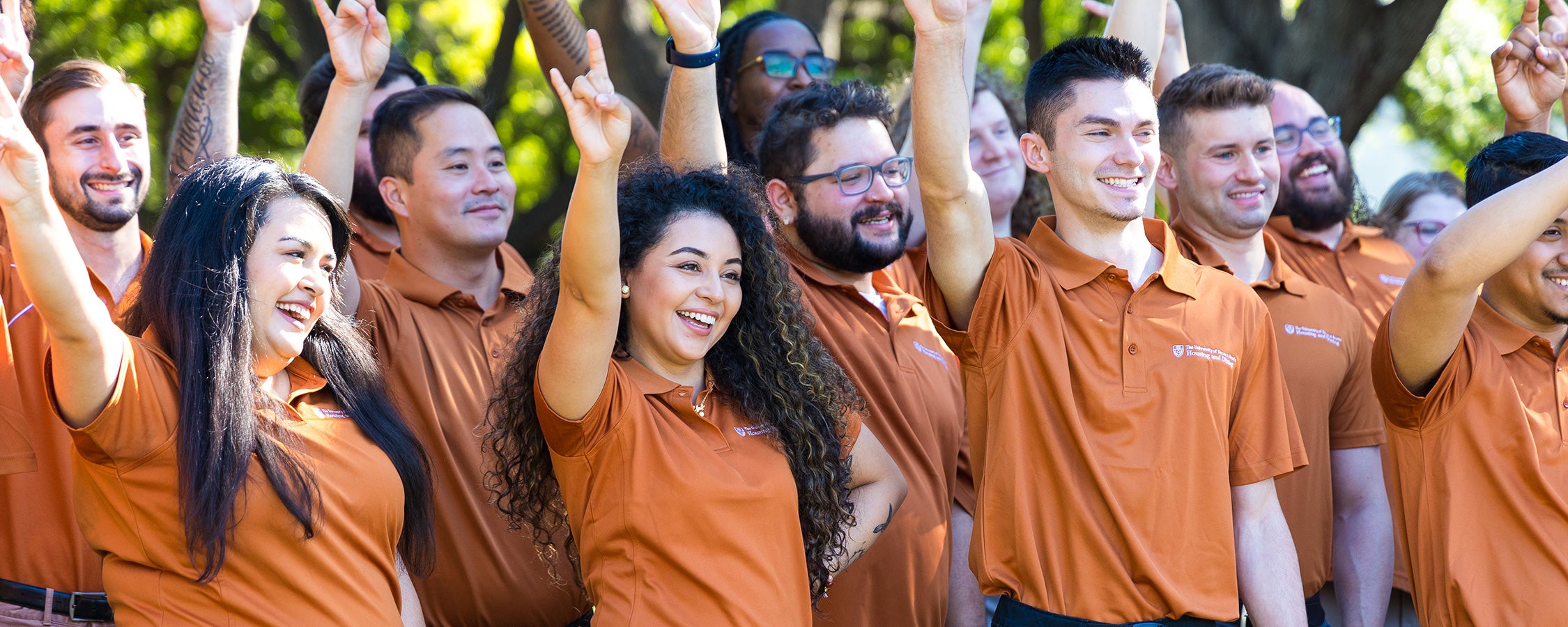 A group of UT residence life staff members pose together while making the Hook ‘em hand sign