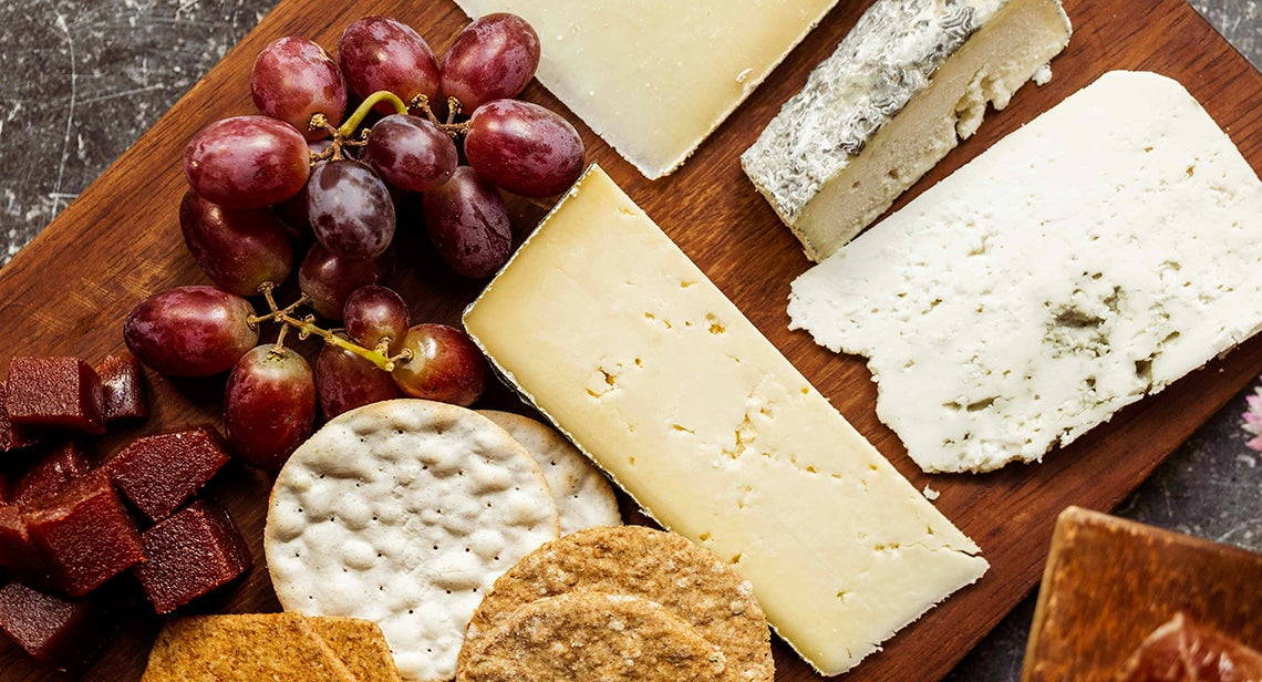 A cheese tray with various crackers and fruits