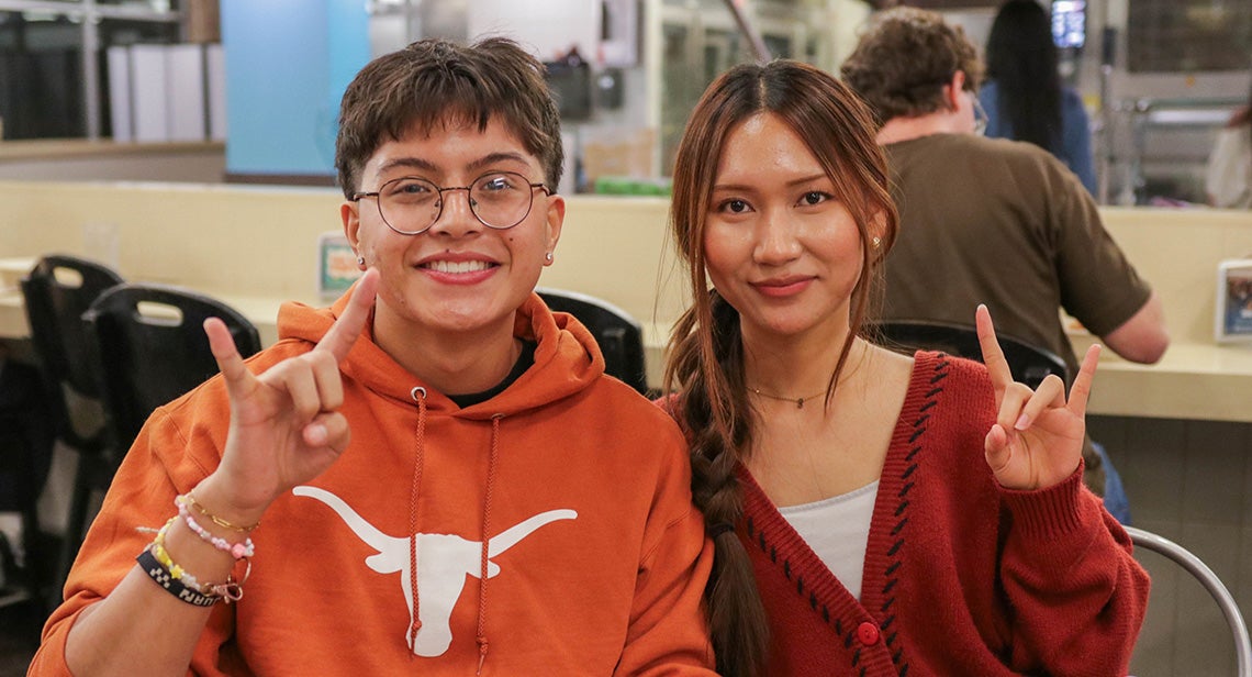 Two UT students pose together while making the Hook ‘Em hand sign