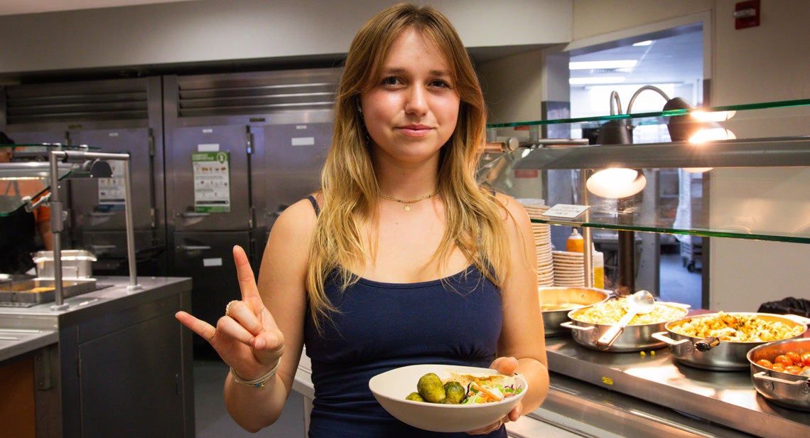 A UHD registered dietitian poses while making the Hook ‘Em hand sign in Kins Dining