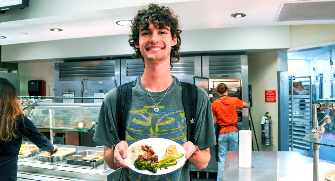 A UT student poses holding a plate of food