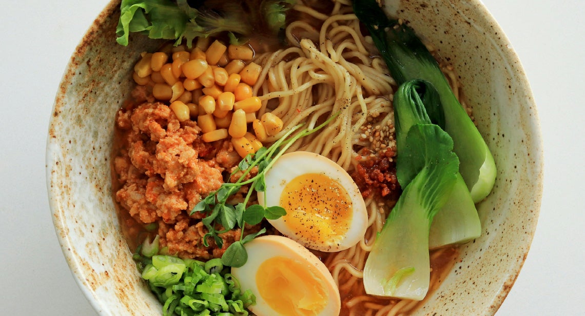 A bowl of ramen with vegetables and eggs. 