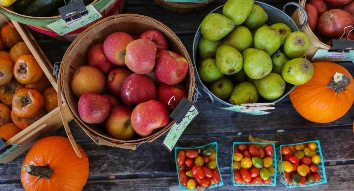 Baskets filled with apples, pears, pumpkins, and cherry tomatoes at a UT Farm Stand market