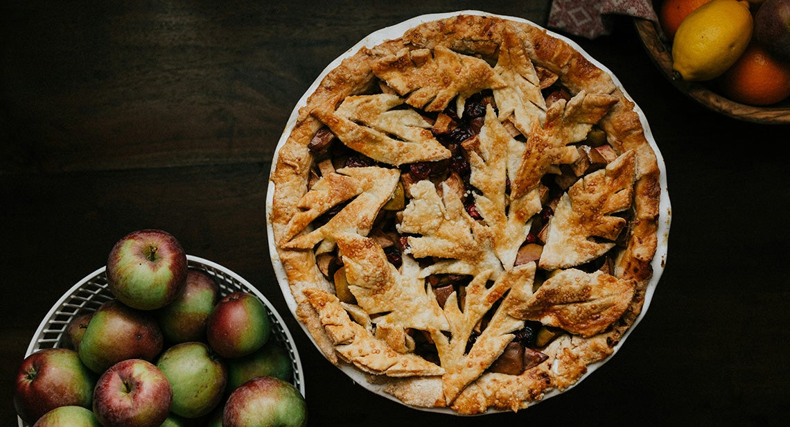A pie next to bowls of fruit.