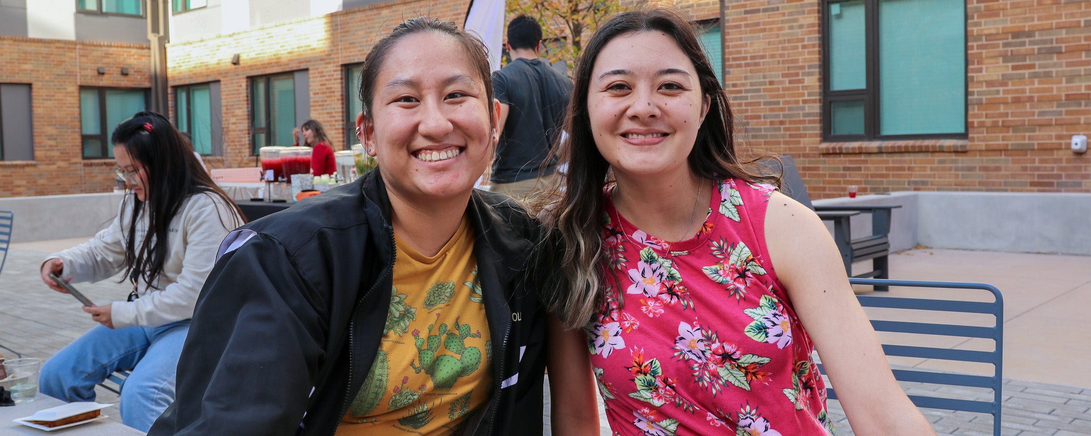 Two students posing with a Hook ‘em hand sign