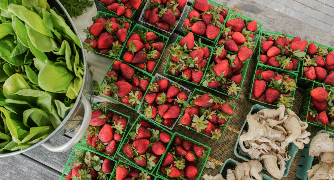 Bok choy, strawberries and mushrooms on a table at a UT Farm Stand market