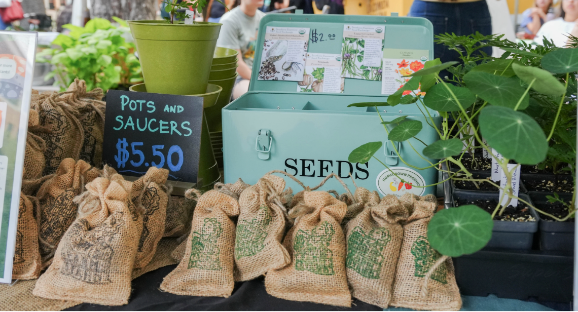 Potted plants and seed packets on a table at a UT Farm Stand market