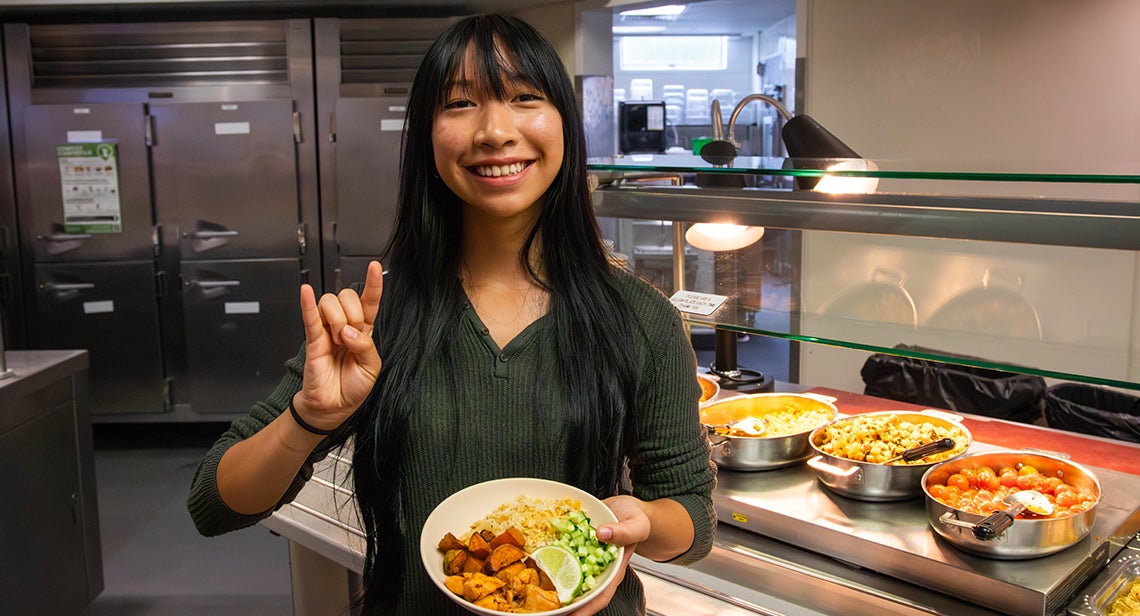 A UT student makes the Hook ‘em hand sign while holding a plate. 