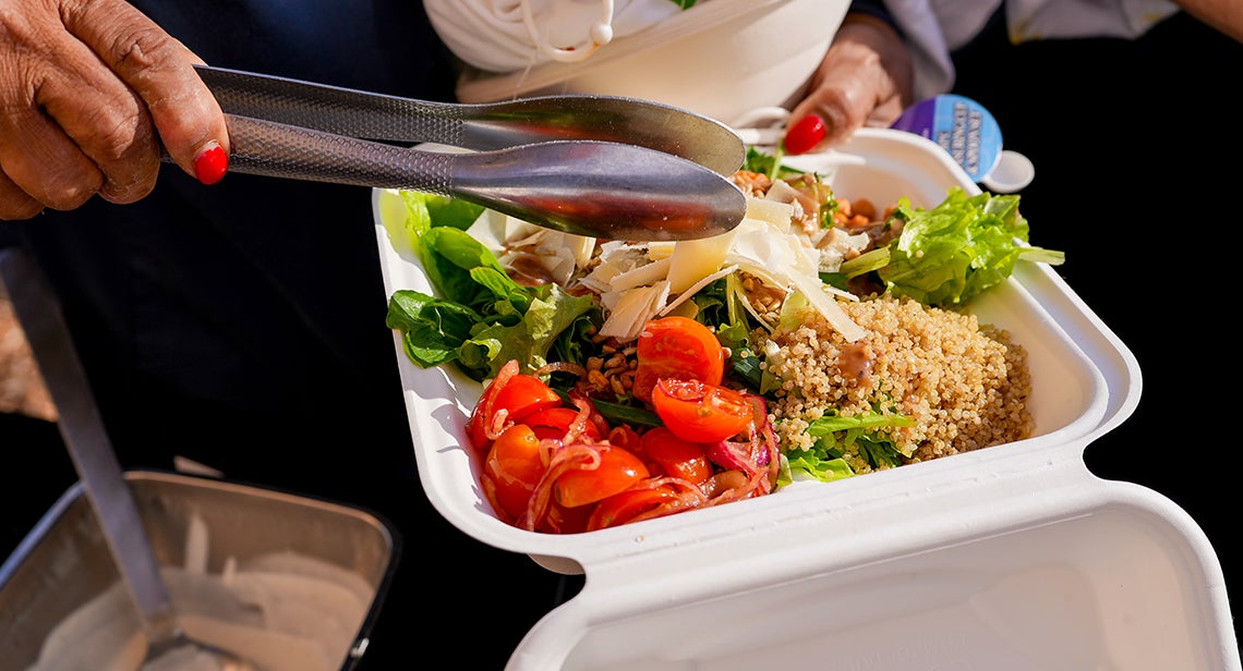A close up view of a quinoa salad bowl being mixed. 