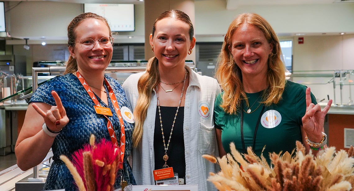 A group of UHD registered dietitians and a UT student pose together while making the Hook ‘Em hand sign at a Creation Kitchen event in Kins Dining