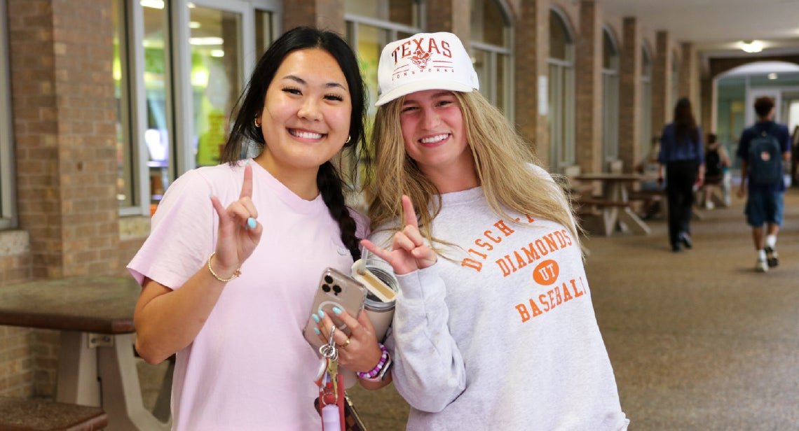 Two UT students make the Hook ‘Em hand sign at Jester Plaza