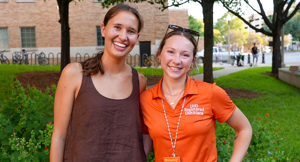 A UT student poses with a UHD registered dietitian in front of San Jacinto Hall.