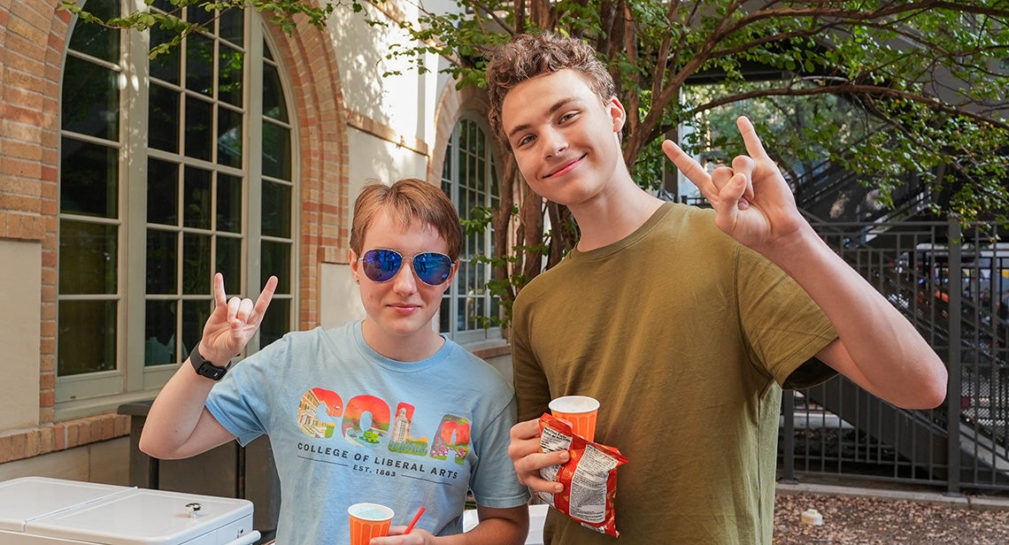 Two UT students pose together while making the Hook ‘em hand sign in front of BRP.
