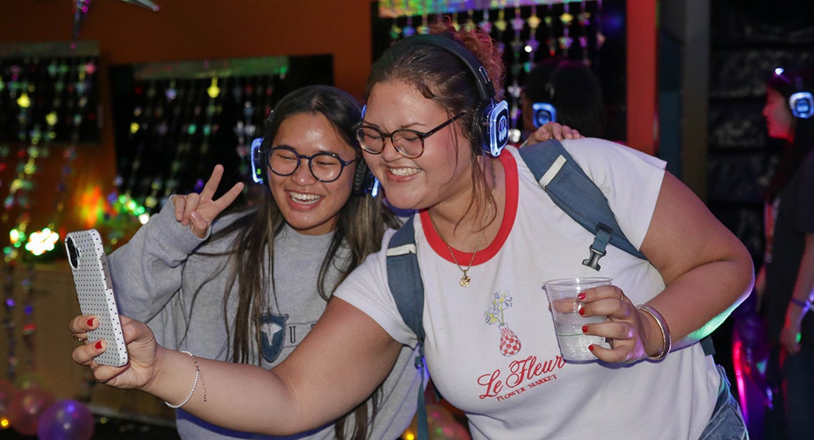 Two UT students take a selfie together at a silent disco event.