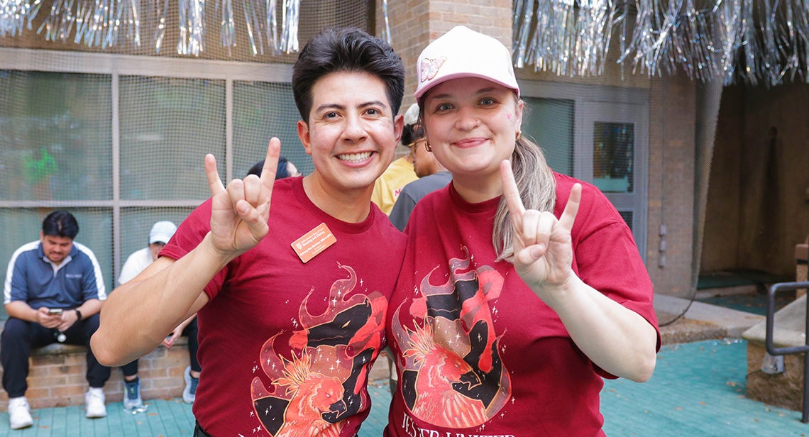 Two UT students pose together while making the Hook ‘em hand sign at Jester Plaza.