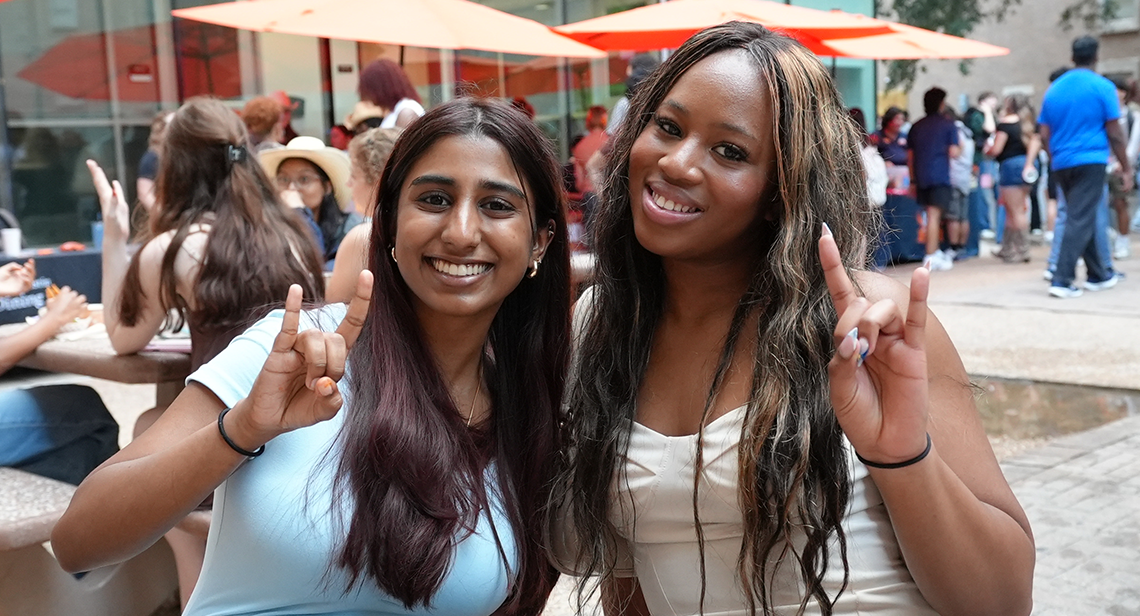 Two UT students pose together while making the Hook ‘Em hand sign at Jester Plaza during the Texas Block Party event