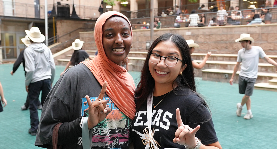 Two UT students pose together while making the Hook ‘Em hand sign at Jester Plaza during the Texas Block Party event